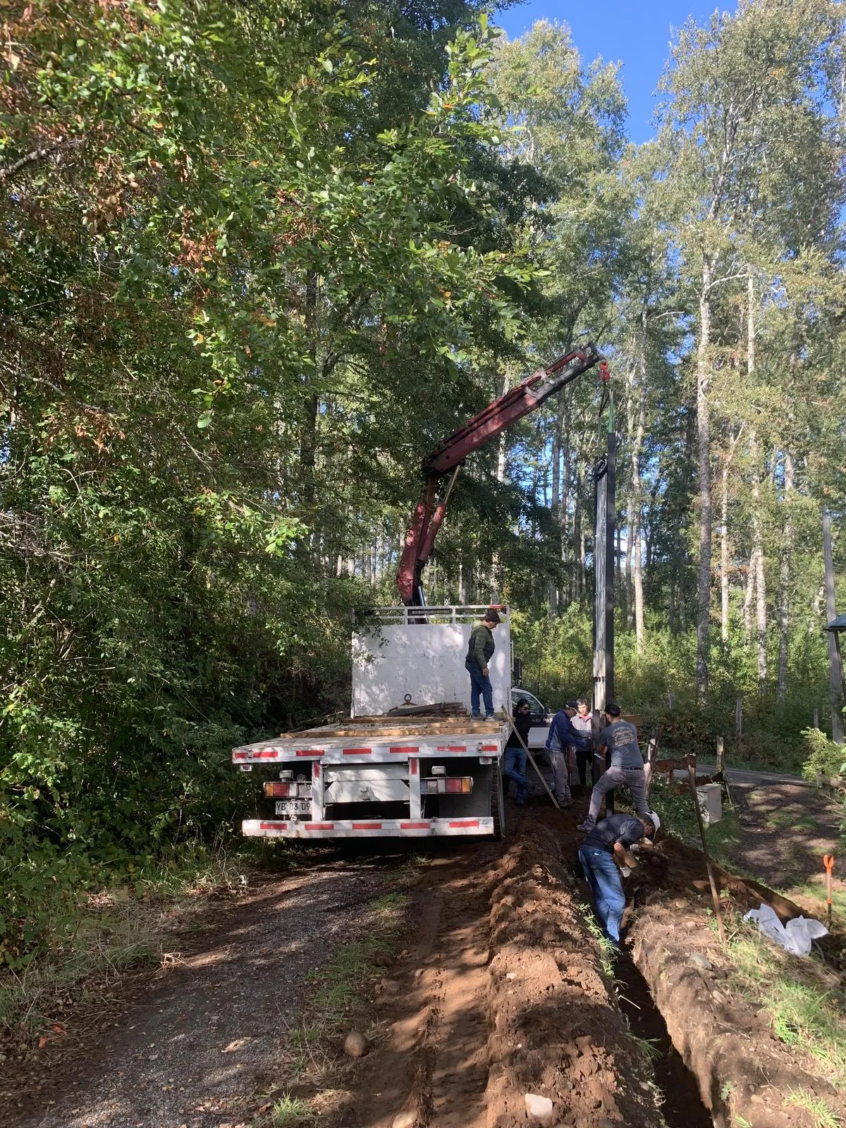 Camión grúa instalando poste de acometida eléctrica en sector rural de La Araucanía