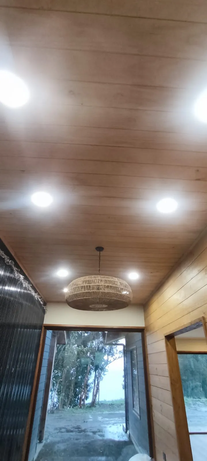 Iluminación colgante y focos embutidos en corredor de casa de campo