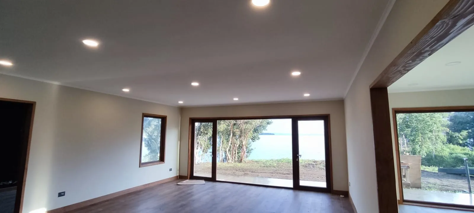 Instalación eléctrica en living con ventanales al lago, proyecto residencial zona lacustre