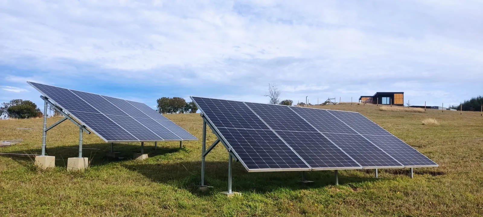 Dos arreglos de paneles solares instalados en campo abierto, zona lacustre La Araucanía